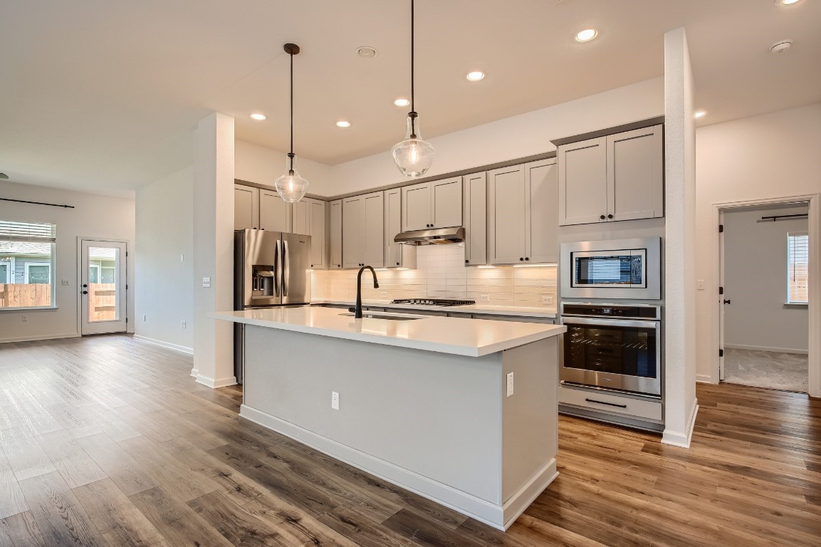 7904 Gilwice Lane Austin, TX 78744 - Photo 5 of 24 a kitchen with stainless steel appliances granite countertop a refrigerator a oven a sink and white cabinets with wooden floor