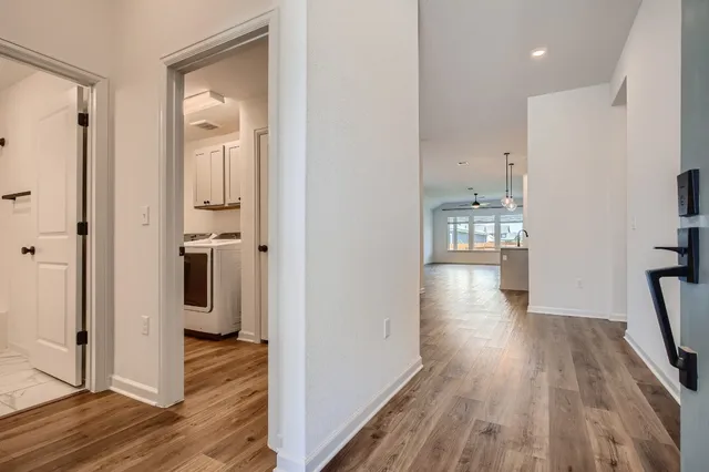 a view of a hallway with wooden floor and a living room
