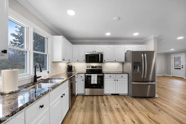 a kitchen with stainless steel appliances granite countertop a refrigerator a sink a stove a microwave and wooden cabinets