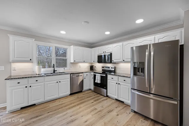 a kitchen with granite countertop stainless steel appliances a refrigerator sink and cabinets