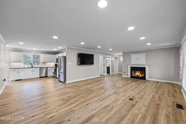 a view of a big room with wooden floor and a kitchen