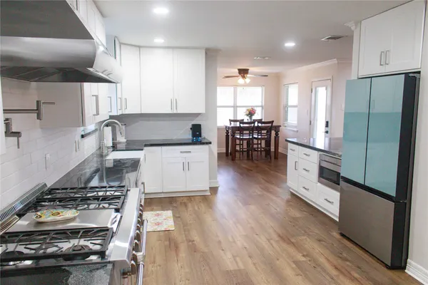 a kitchen with stainless steel appliances granite countertop a stove a sink and a white cabinets