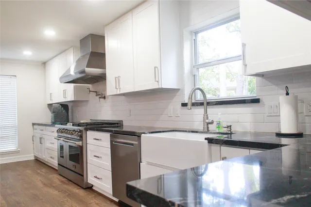 a kitchen with stainless steel appliances granite countertop a stove a sink and a white cabinets
