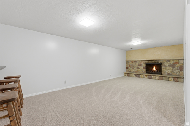 148 Tennyson Avenue Sandy, UT 84070 - Photo 28 of 55 Spacious room featuring a stone-faced fireplace with a raised hearth, light-toned carpeting, and recessed ceiling lighting
