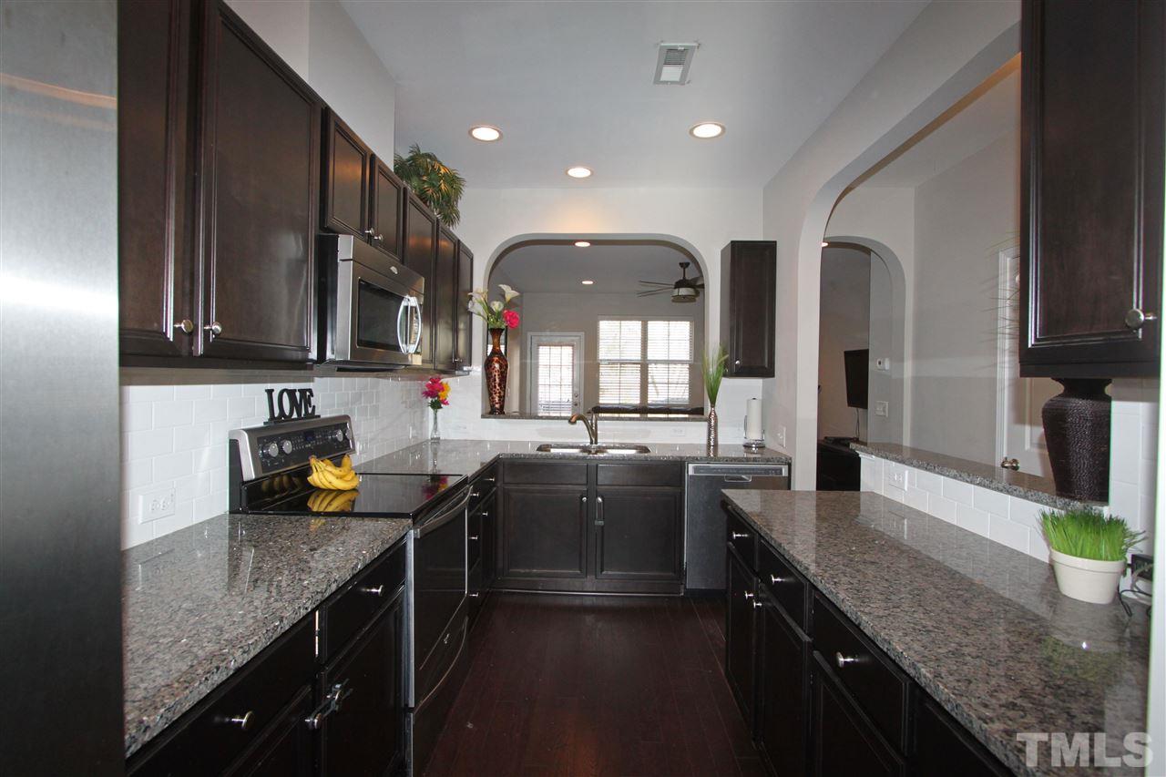 760 Wickham Ridge Road Apex, NC 27539 - Photo 5 of 25 a kitchen with granite countertop a sink a stove and cabinets