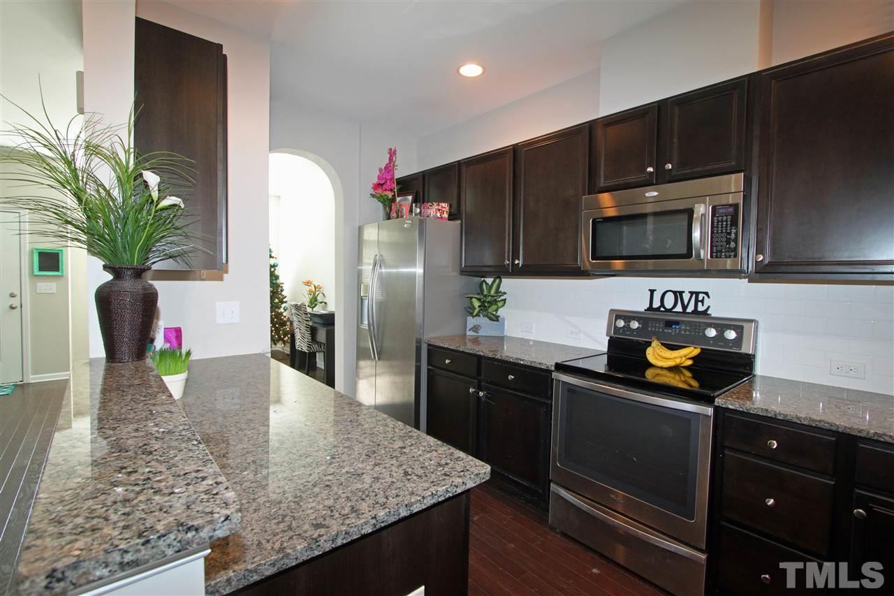 760 Wickham Ridge Road Apex, NC 27539 - Photo 6 of 25 a kitchen with granite countertop a refrigerator a stove a microwave a sink and cabinets