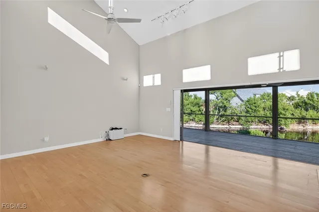 a view of an empty room with a window and wooden floor