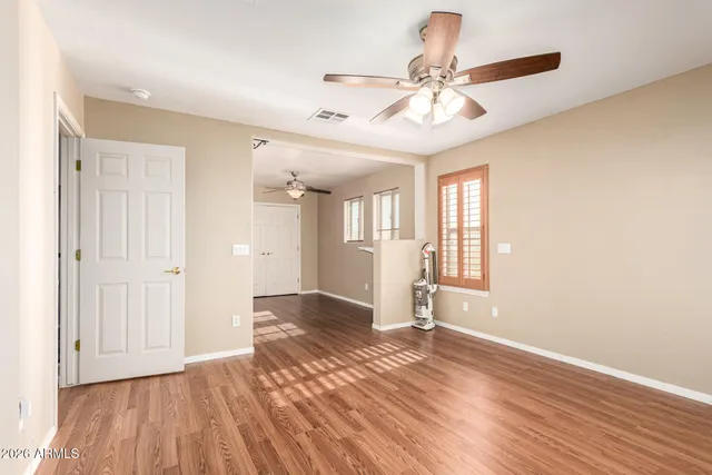 an empty room with wooden floor fan and windows