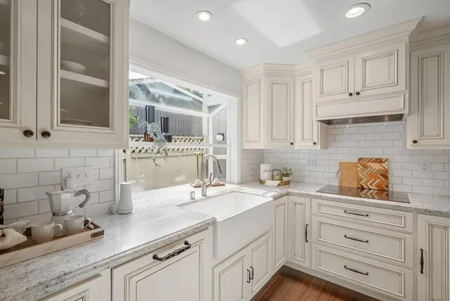 a kitchen with white cabinets and sink