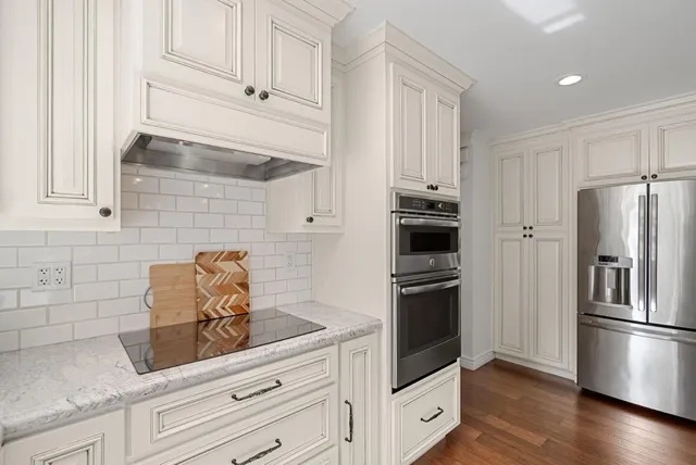 a kitchen with granite countertop white cabinets and stainless steel appliances