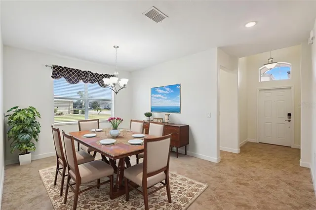 a view of a dining room with furniture a potted plant and a window
