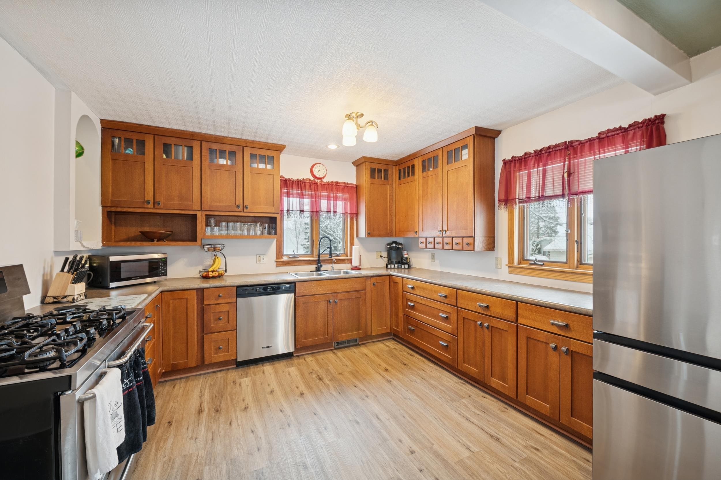 220 5th Avenue West Washburn, WI 54891 - Photo 6 of 38 Kitchen featuring stainless steel appliances, brown cabinetry, light wood-style floors, beamed ceiling, and a textured ceiling