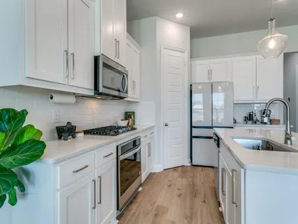 a kitchen with stainless steel appliances granite countertop a sink a stove and a refrigerator