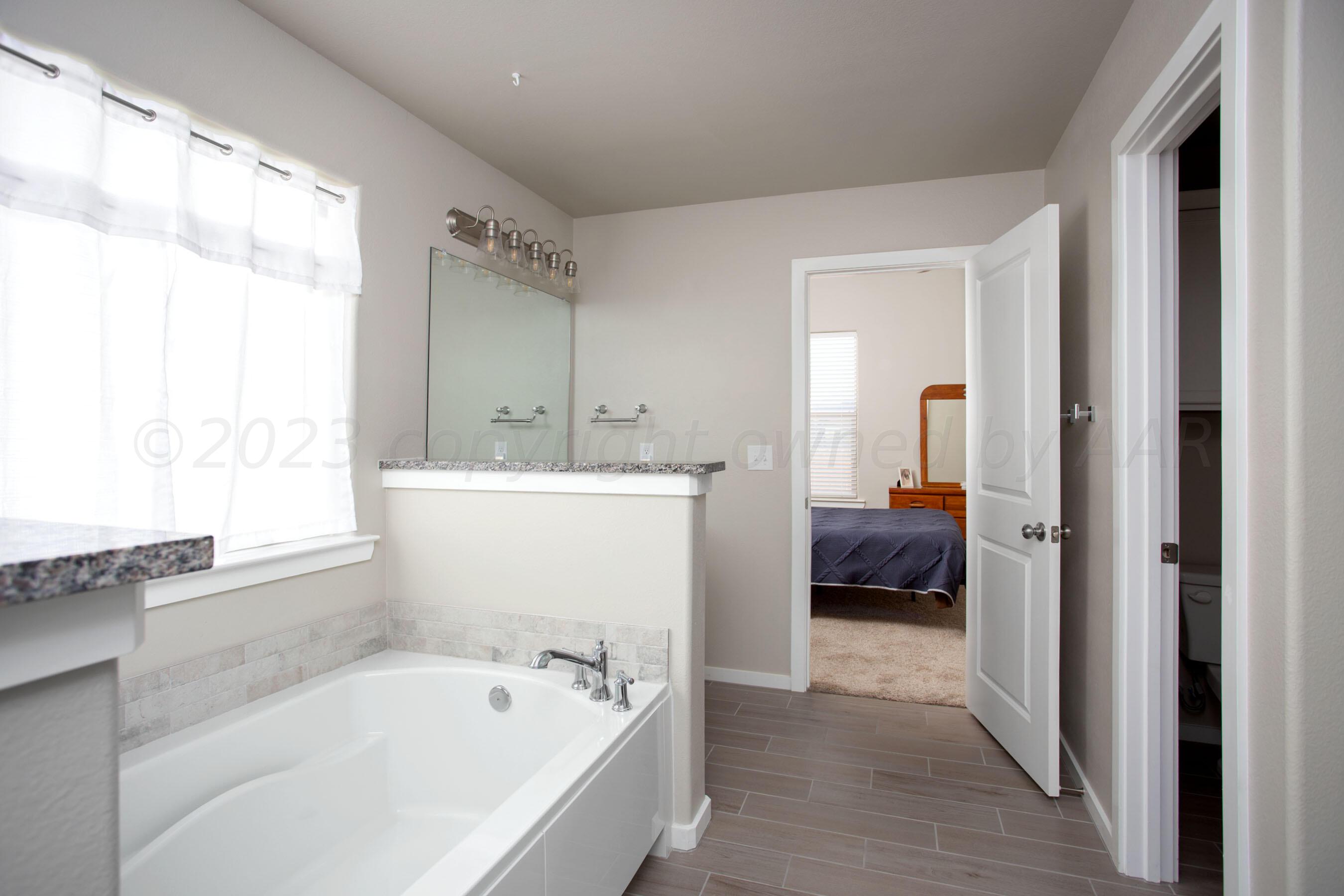7811 Bellamy Drive Amarillo, TX 79119 - Photo 14 of 24 a en suite bathroom with a tub sink and a mirror