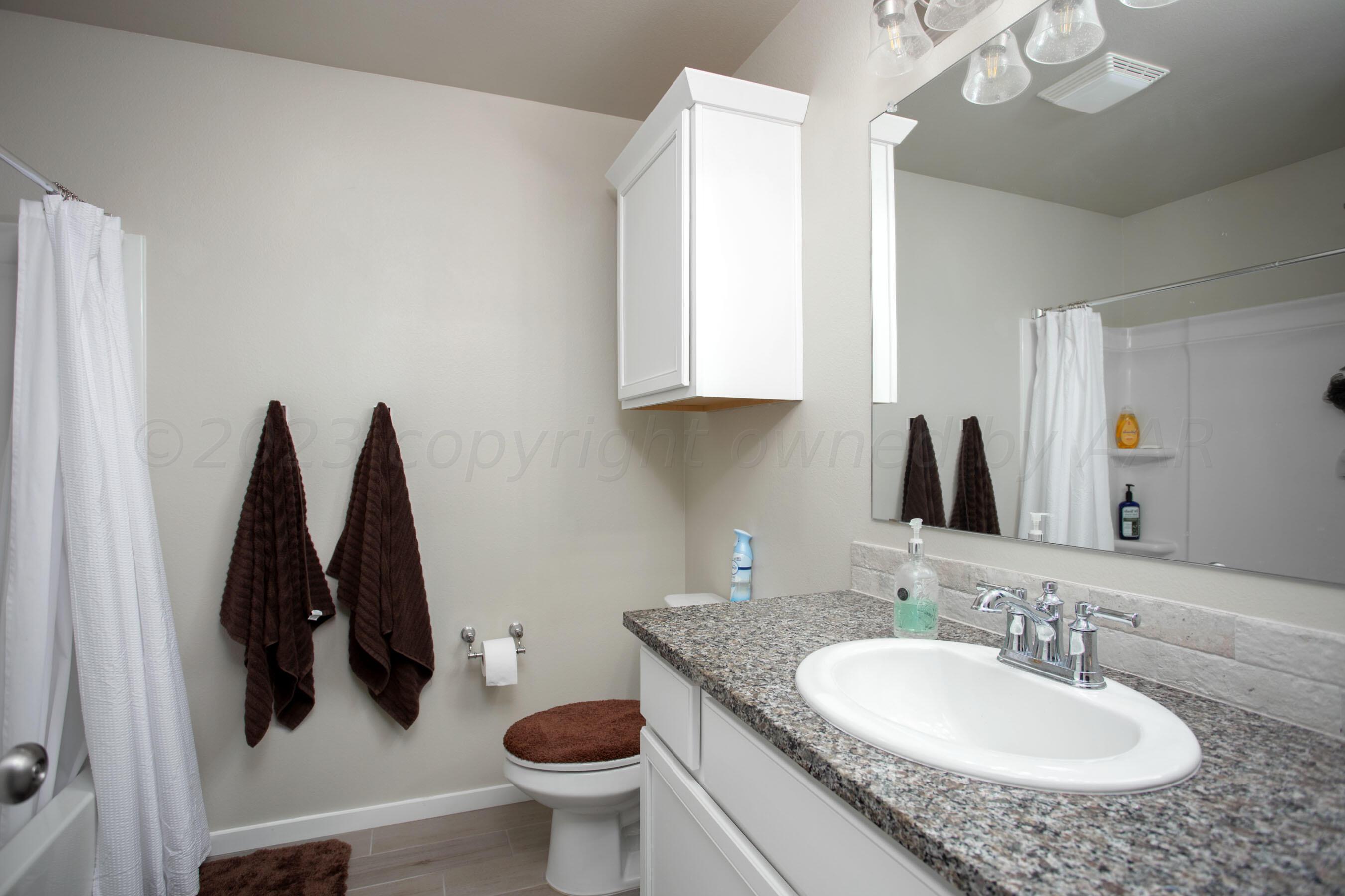 7811 Bellamy Drive Amarillo, TX 79119 - Photo 18 of 24 a bathroom with a granite countertop sink and a mirror
