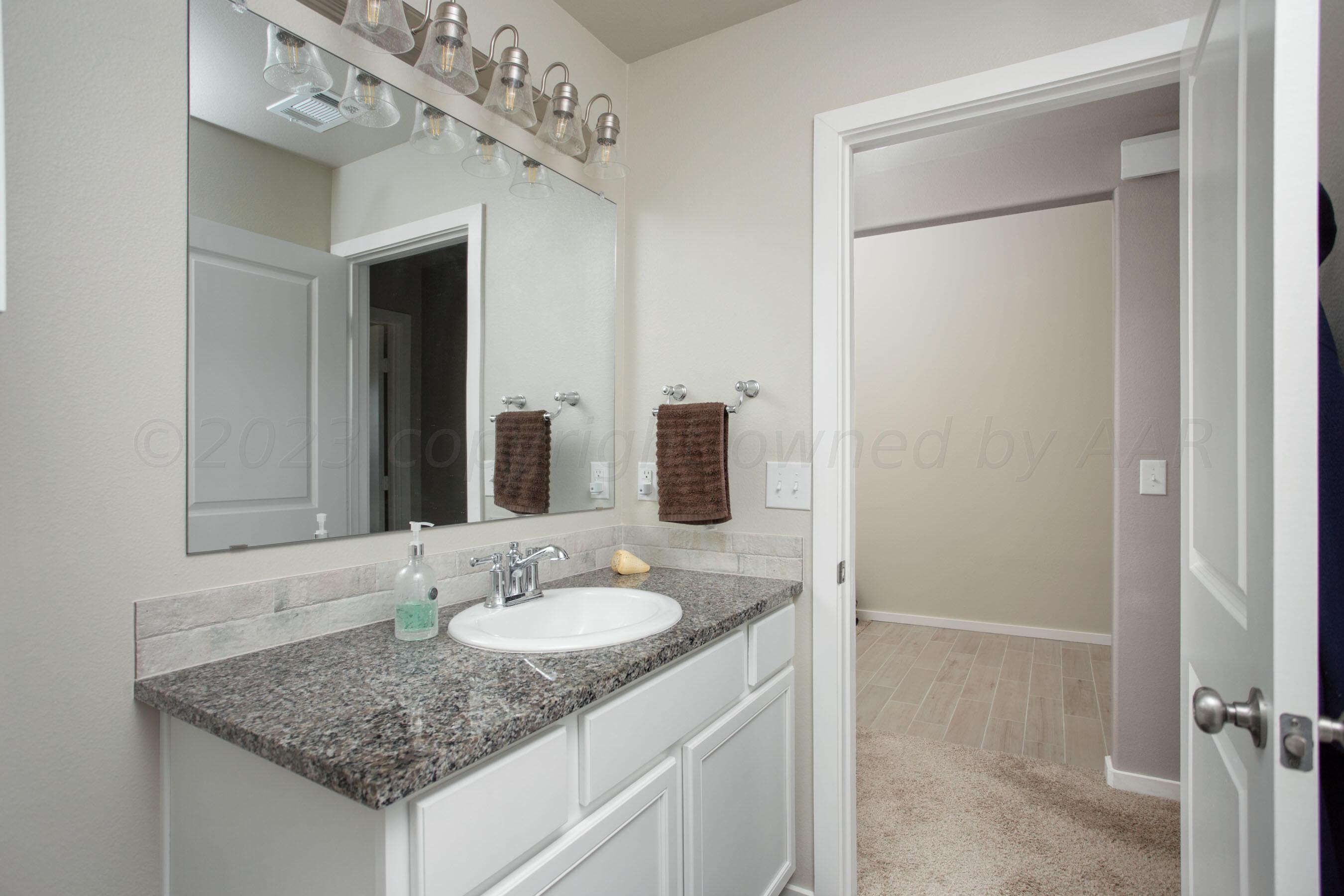 7811 Bellamy Drive Amarillo, TX 79119 - Photo 19 of 24 a bathroom with a granite countertop sink and a mirror