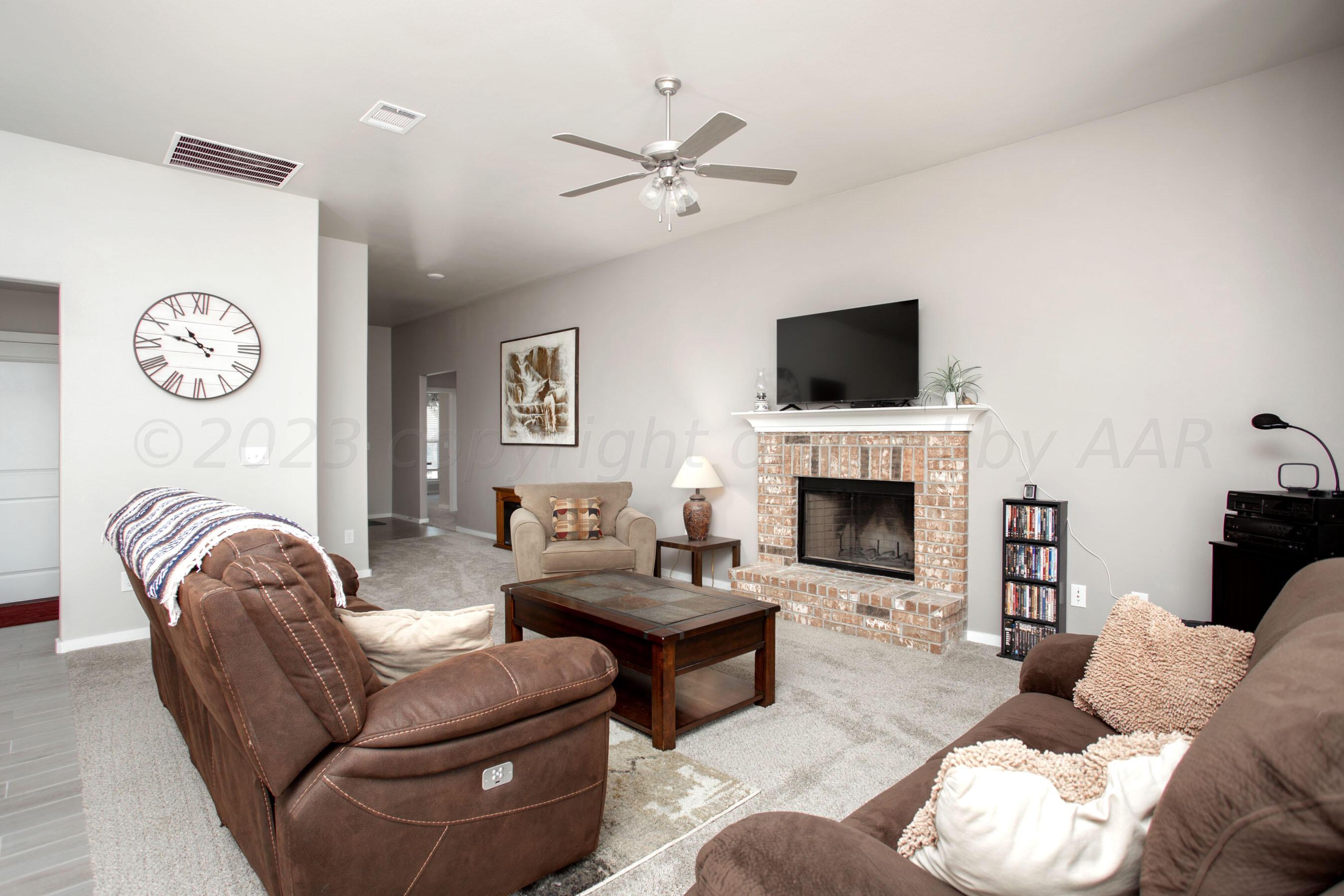 7811 Bellamy Drive Amarillo, TX 79119 - Photo 3 of 24 a living room with furniture a fireplace and a flat screen tv