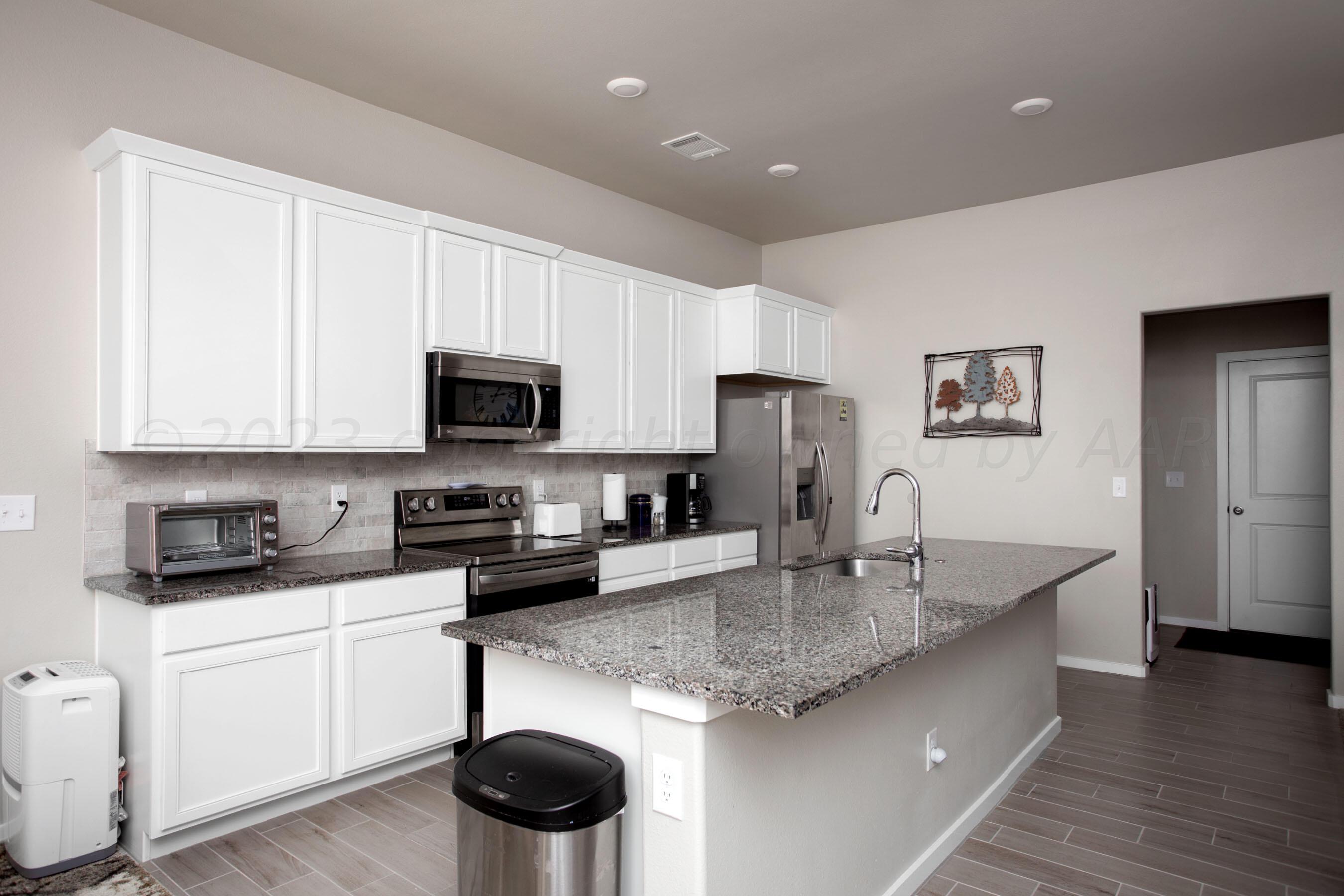 7811 Bellamy Drive Amarillo, TX 79119 - Photo 6 of 24 a kitchen with stainless steel appliances granite countertop a sink a stove a microwave a refrigerator a counter space and cabinets