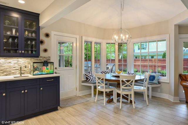 a dining room with wooden floor a chandelier a glass table and chairs