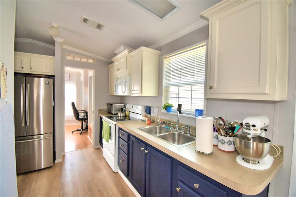 251 Patterson Road, Unit I58 Haines City, FL 33844 - Photo 17 of 52 a kitchen with stainless steel appliances granite countertop a refrigerator a sink dishwasher a stove and white countertops with wooden floor