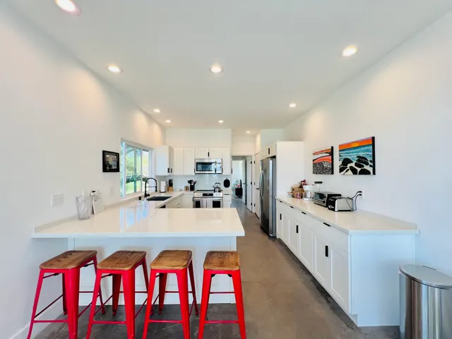 a large white kitchen with sink a stove and white cabinets