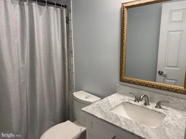 a bathroom with a granite countertop sink toilet and a mirror