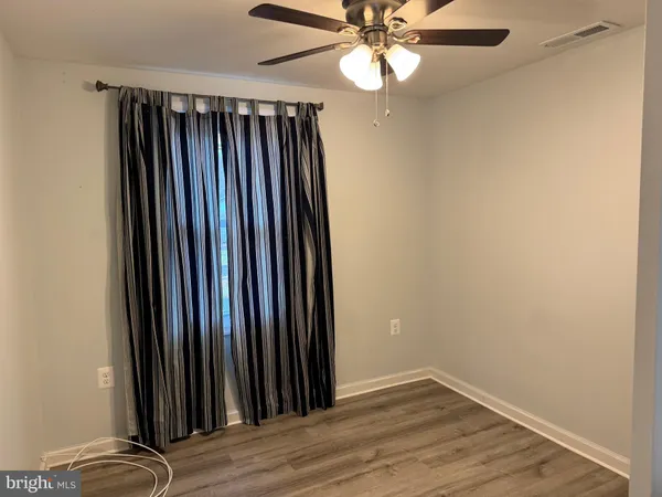 an empty room with wooden floor fan and windows