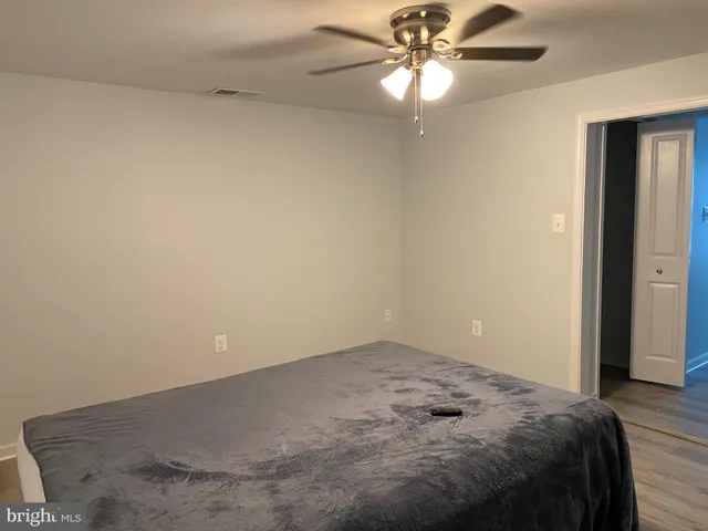 wooden floor in a bedroom next to a bed and a ceiling fan