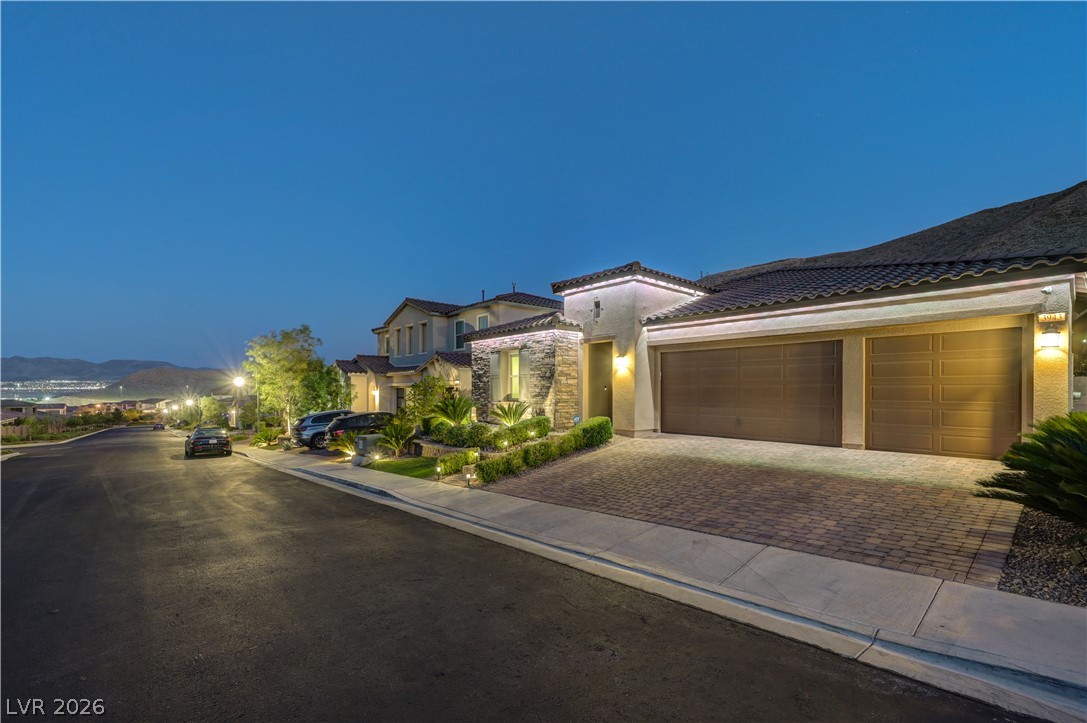 3943 Reyes Avenue Las Vegas, NV 89141 - Photo 88 of 95 Illuminated by night, this home showcases a paver block driveway leading to a spacious garage.