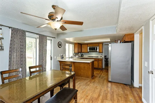 a kitchen with stainless steel appliances granite countertop a refrigerator a sink dishwasher a stove and white countertops with wooden floor