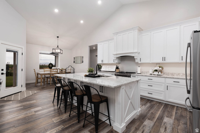 186 West 580 North Redmond, UT 84652 - Photo 12 of 74 Kitchen with light stone counters, a center island with sink, white cabinets, stainless steel appliances, and vaulted ceiling