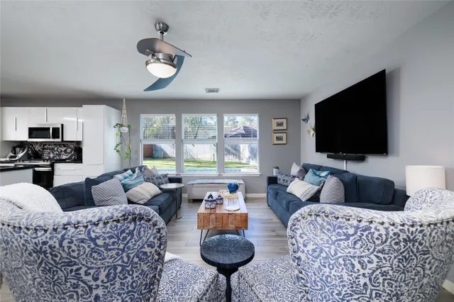 a living room with furniture a flat screen tv and a large window