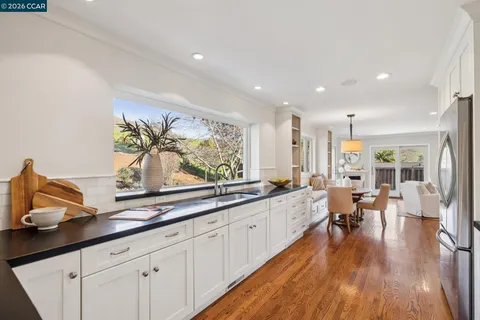 a kitchen with a refrigerator a stove a dining table and chairs with wooden floor