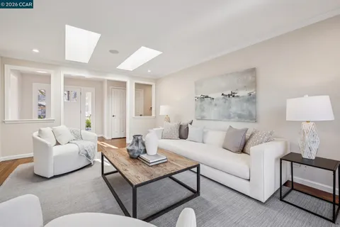 a large living room with stainless steel appliances furniture a large window and wooden floor