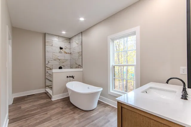 a bathroom with a sink and mirror with bathtub