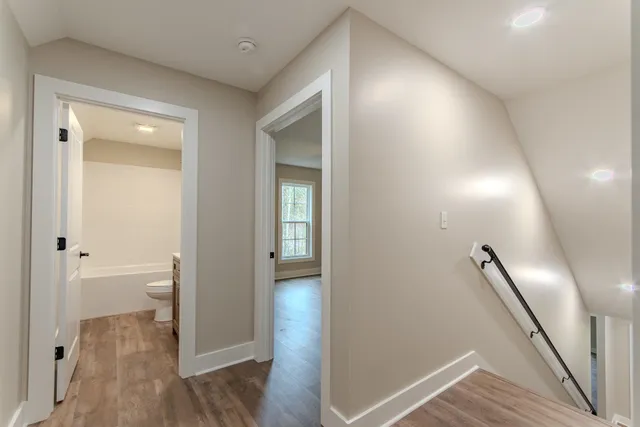 a view of a hallway with wooden floor and a bathroom