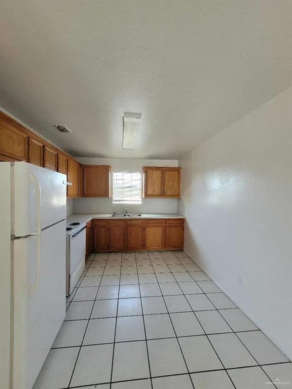 1612 Orange Avenue, Unit 13 Weslaco, TX 78596 - Photo 2 of 12 Kitchen featuring sink, white appliances, a textured ceiling, and light tile patterned flooring