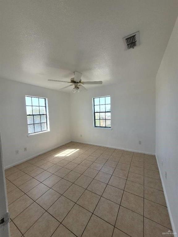 1612 Orange Avenue, Unit 13 Weslaco, TX 78596 - Photo 8 of 12 Empty room featuring ceiling fan, a textured ceiling, and a wealth of natural light