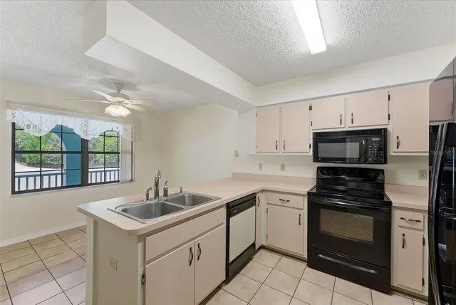 a view of an empty room with window and chandelier fan
