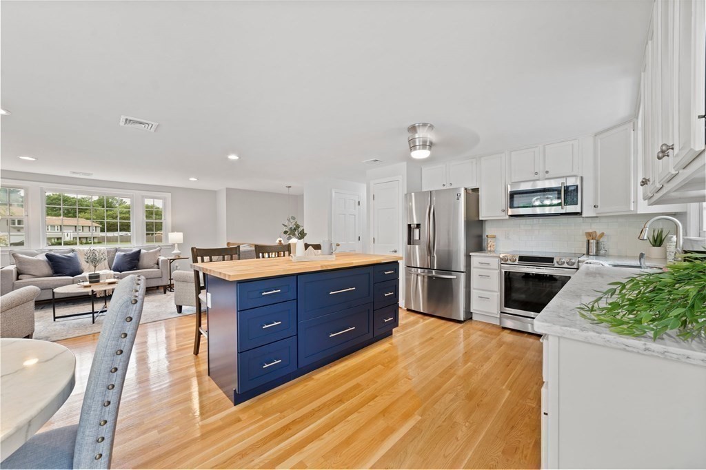 56 Cedarcrest Road Hanover, MA 02339 - Photo 8 of 26 a kitchen with stainless steel appliances kitchen island granite countertop a stove top oven a sink dishwasher a dining table and chairs with wooden floor