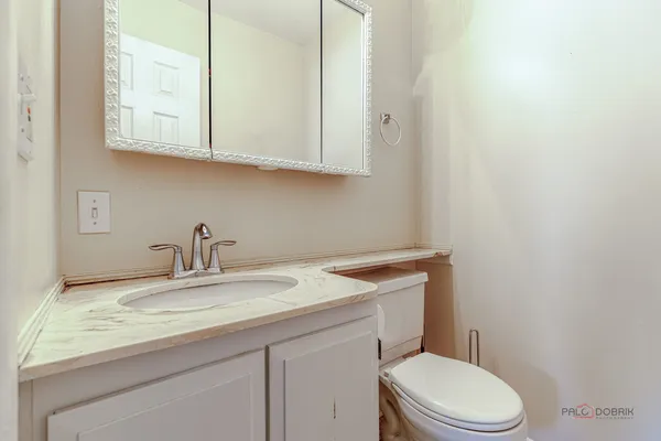 a bathroom with a granite countertop toilet sink mirror and vanity