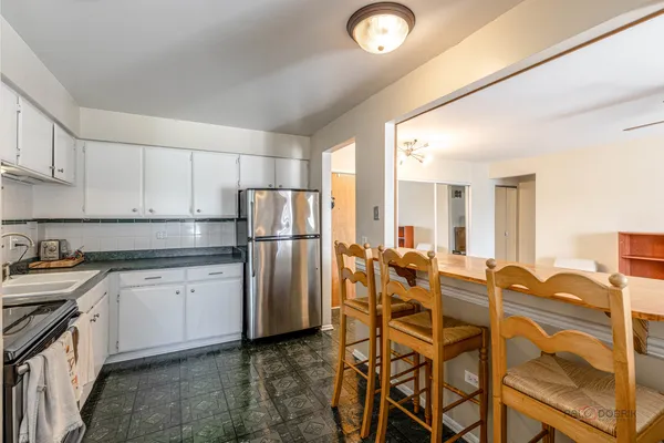a kitchen with stainless steel appliances granite countertop a refrigerator a stove a sink and white cabinets with wooden floor