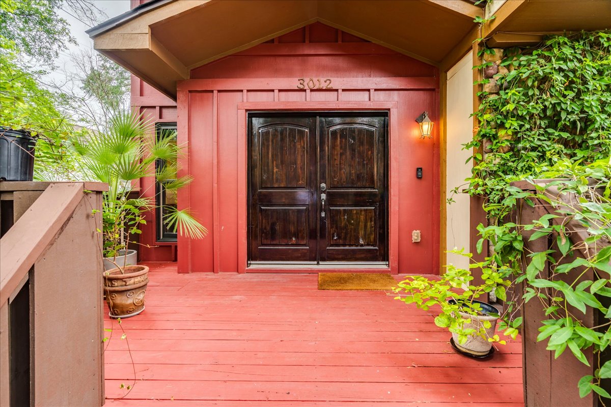 3012 South 4th Street, Unit B Austin, TX 78704 - Photo 36 of 40 Inviting entrance featuring double dark wood doors, a warm red exterior, and a coordinating red-stained wooden deck