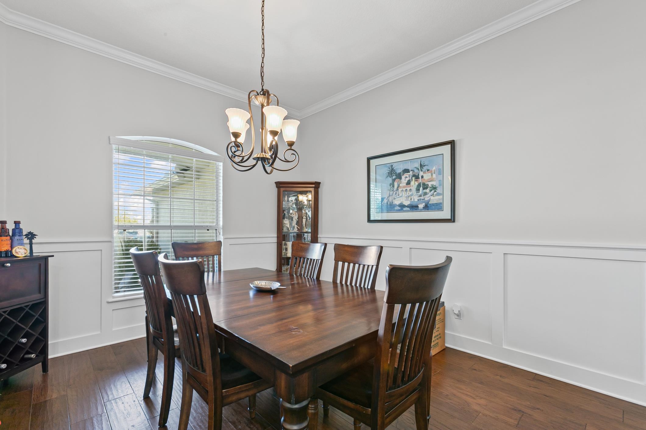 2724 North Portofino Road St. Augustine, FL 32092 - Photo 22 of 86 Dining room with a decorative wall, dark wood-style floors, a wainscoted wall, ornamental molding, and a chandelier