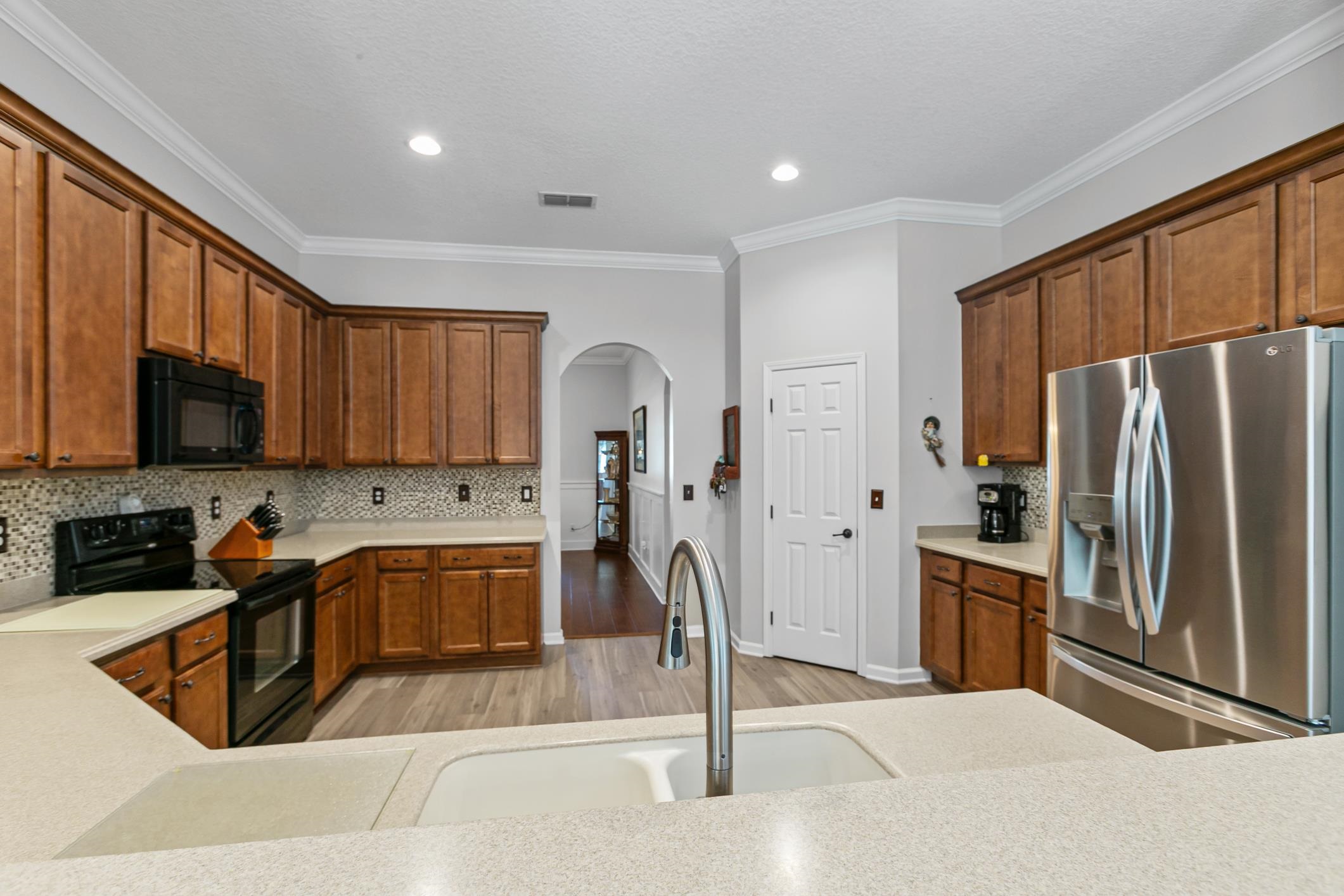 2724 North Portofino Road St. Augustine, FL 32092 - Photo 26 of 86 Kitchen featuring black appliances, tasteful backsplash, ornamental molding, light wood-style flooring, and arched walkways