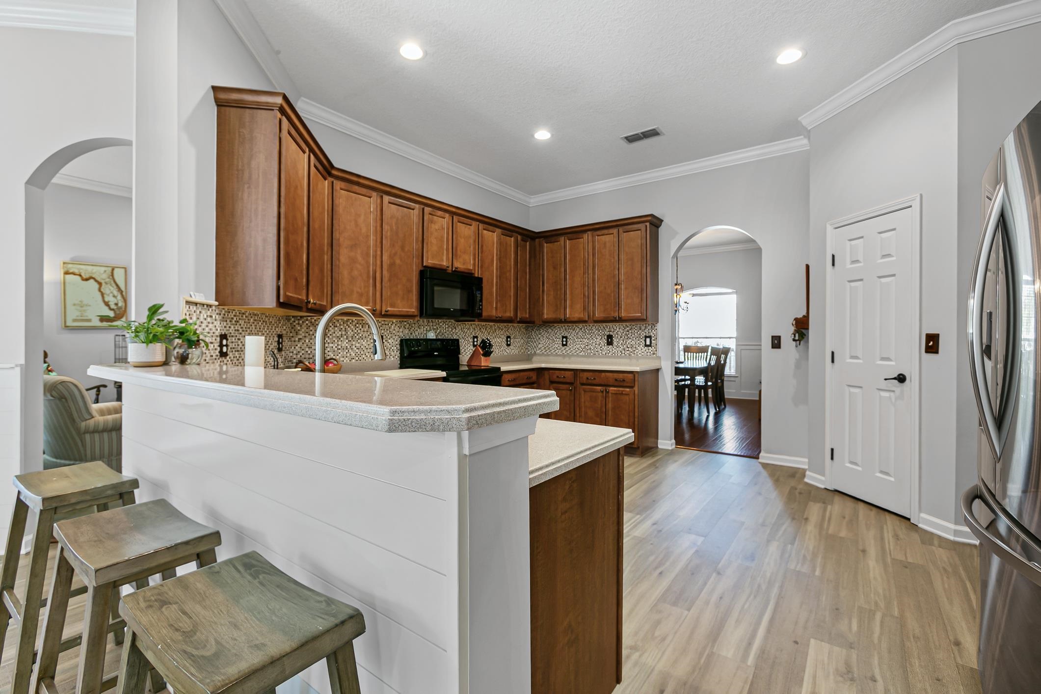 2724 North Portofino Road St. Augustine, FL 32092 - Photo 27 of 86 Kitchen with arched walkways, brown cabinets, a breakfast bar, a peninsula, and crown molding