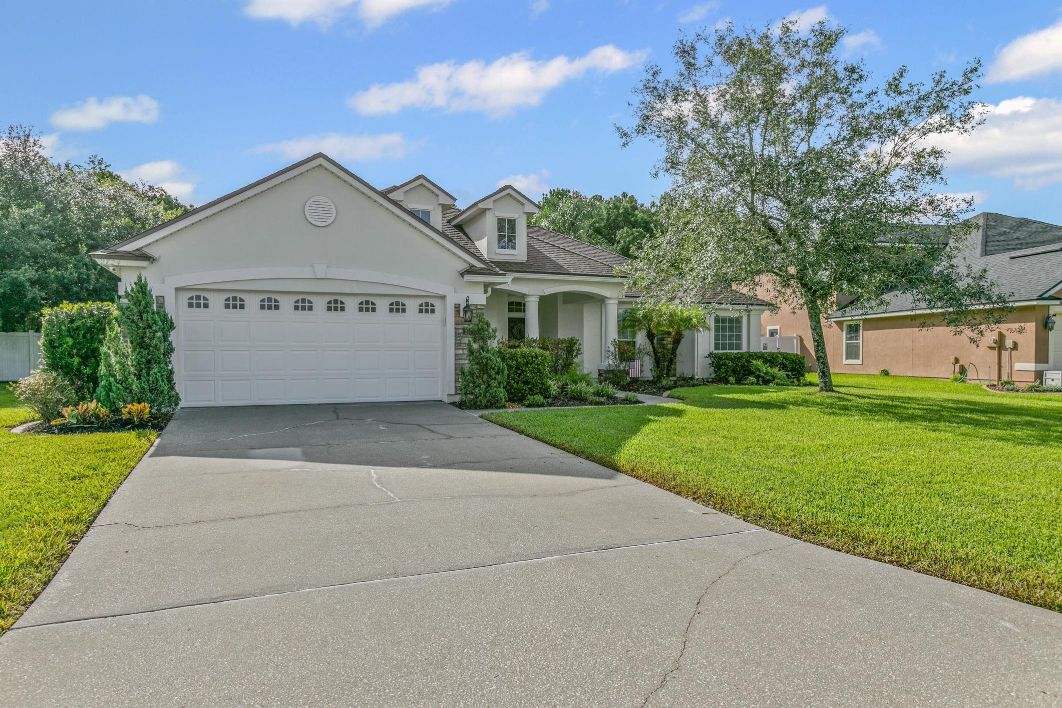 2724 North Portofino Road St. Augustine, FL 32092 - Photo 3 of 86 View of front of home featuring stucco siding, driveway, a front lawn, and a garage