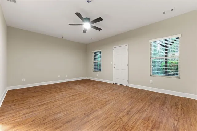 an empty room with wooden floor and windows