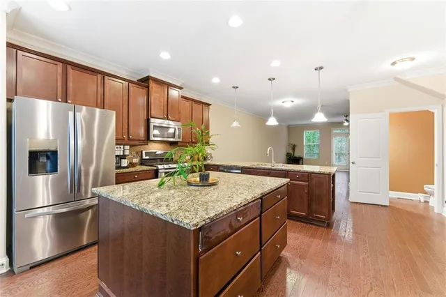 a kitchen with stainless steel appliances granite countertop a refrigerator a sink and a stove