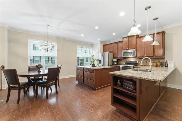 a kitchen with granite countertop kitchen island stainless steel appliances a dining table and chairs